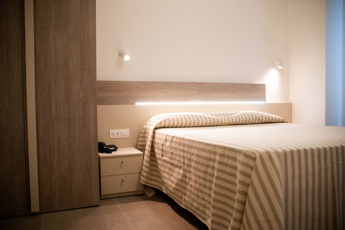 A bedroom with a bed, bedside table, and a nightstand.
