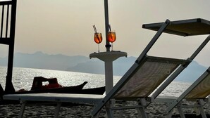 A beachside lounge area with two sun loungers and a table with two drinks. - Blu Hotel  (Pontecagnano Faiano)
