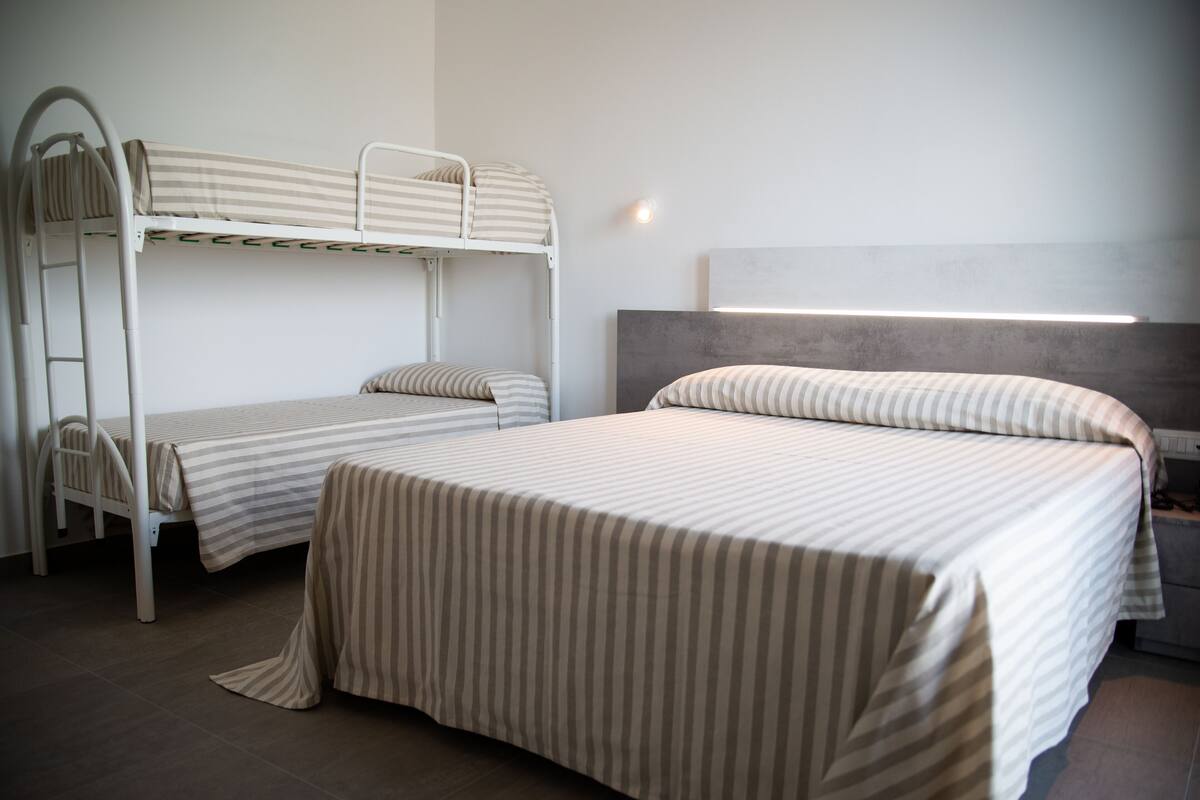 A room with two bunk beds, a desk, and a chair.