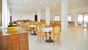 A spacious dining area with multiple tables and chairs, large windows, and a clean, modern interior. - Blu Hotel  (Pontecagnano Faiano)