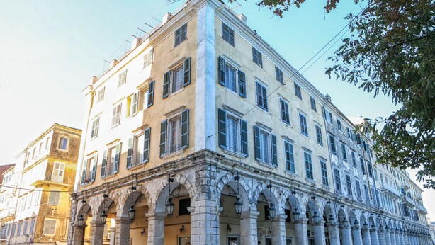 Un edificio histórico con varios pisos, grandes ventanales y un patio central con arcos.