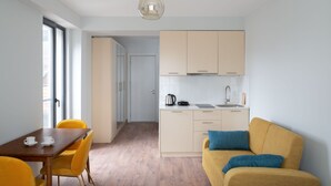 A compact living space with a dining area, kitchenette, and a sofa with cushions. - Gudauri Ski Resort - Twins Apartments (Kazbegi)