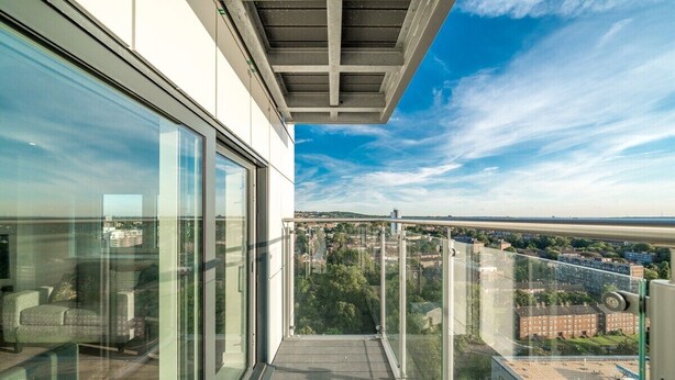 A balcony with a glass railing overlooking a cityscape.