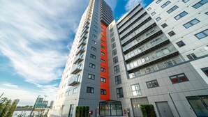 A modern high-rise building with a prominent red vertical stripe, large windows, and a flat roof.