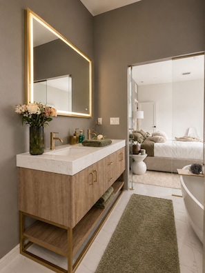 Un baño moderno con lavamanos de mármol, tocador de madera y un espejo grande.
