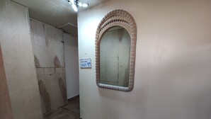 A hallway with a wooden floor, a large mirror with a wicker frame, and a sign that says "Life is just BEACHY." - 2 bedroom one bath  holiday FL
 (Holiday)