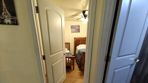 A narrow hallway with wooden flooring leading to a bedroom with a bed and an American flag on the wall. - 2 bedroom one bath  holiday FL
 (Holiday)
