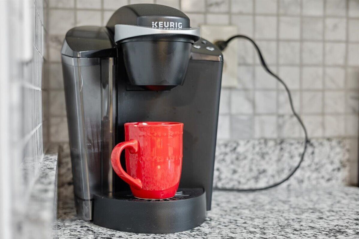 A Keurig coffee machine with a red mug on its drip tray.