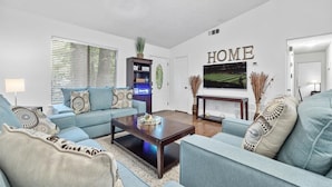 A living room with a sofa set, a coffee table, a TV, and a bookshelf.