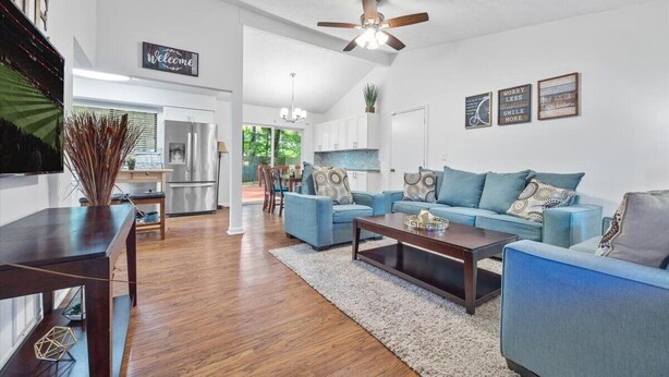 A spacious living area with a blue sofa set, a wooden coffee table, and a ceiling fan.