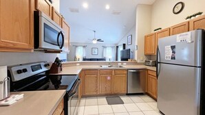 A modern kitchen with wooden cabinets, stainless steel appliances, and a tiled floor. - Sunny pool home with private deck - great location (Davenport)