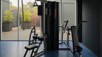 Une salle de sport équipée de matériel d’exercice, avec un banc et une vue sur l’extérieur.