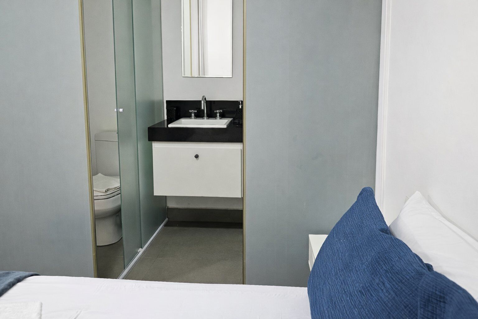 A modern bathroom with a toilet, sink, and mirror.