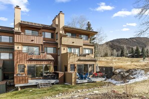 Una moderna casa a più piani con patio, ampie finestre e vista su un paesaggio collinare.