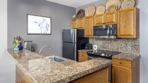 A kitchen with granite countertops, wooden cabinets, a stainless steel refrigerator, and a built-in oven. - Condo in Snowmass Village (Snowmass Village)