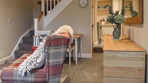 Un escalier avec une rampe en bois, un coin repas avec une table et des chaises, et une horloge murale.