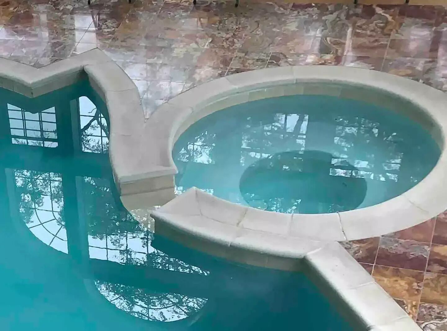 An indoor swimming pool with a circular design and a stone-tiled wall.