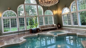 Ein großer, überdachter Pool mit Bogenfenstern und einer Kristallleuchter.