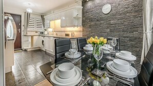 A modern dining area with a stone wall, a clock, and a table set for six with white plates and glasses.