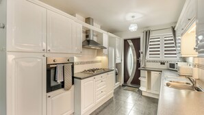 A kitchen with white cabinets, a gas stove, a microwave, and a sink.