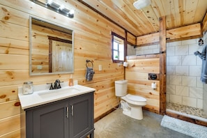 Ein Badezimmer in einer Holzhütte mit Waschbecken, Toilette und Dusche.