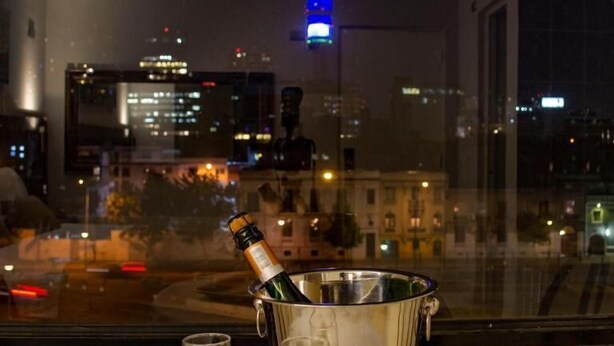 Un balcón con una mesa, una botella de champán y una copa.