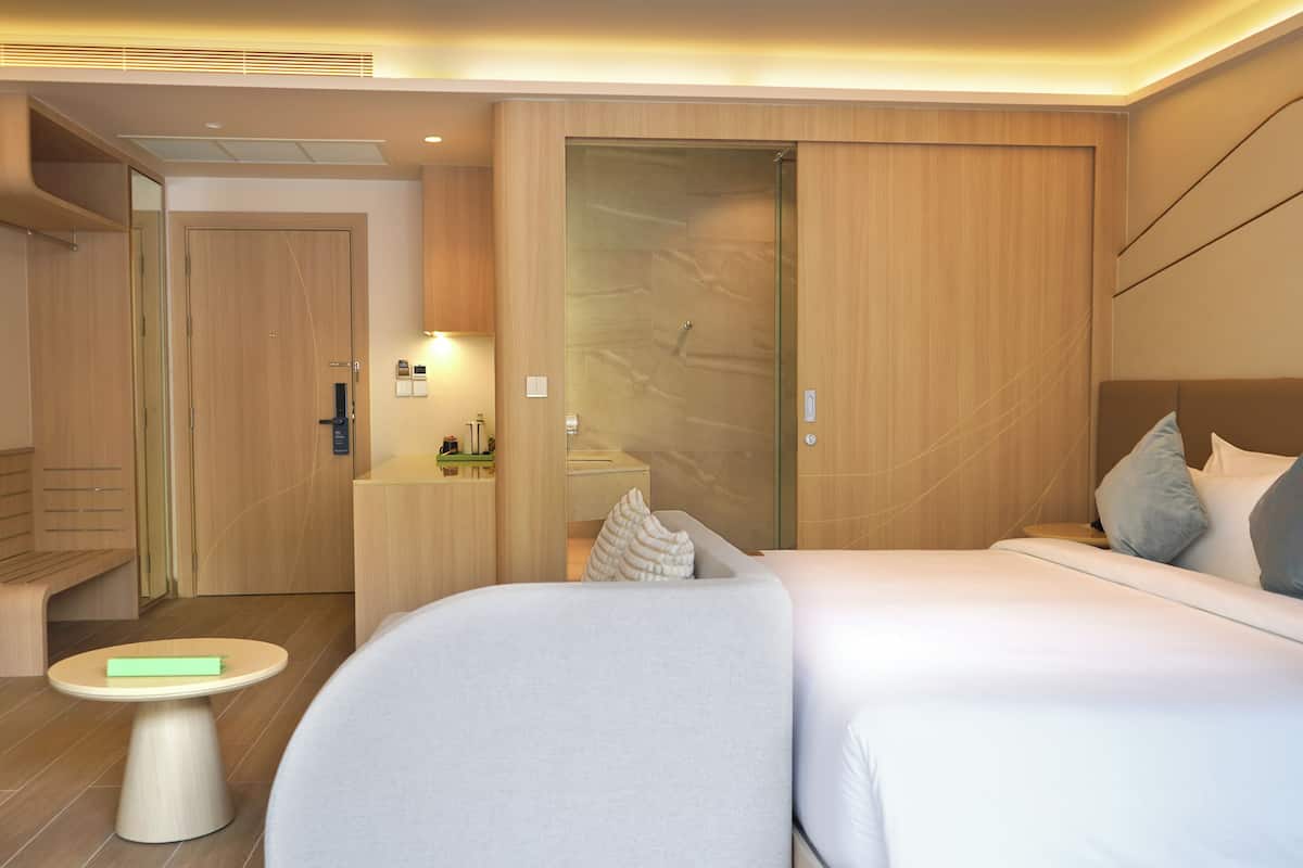 Una habitación de hotel moderna con una cama grande, una mesita pequeña, un escritorio y un armario.