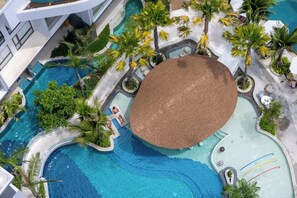 Una gran piscina al aire libre con un toldo circular, rodeada de palmeras y sillas de descanso.