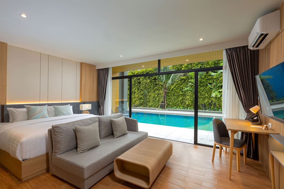 Una habitación de hotel moderna con una cama grande, un sofá, un escritorio con una silla, un televisor y vistas a una piscina.