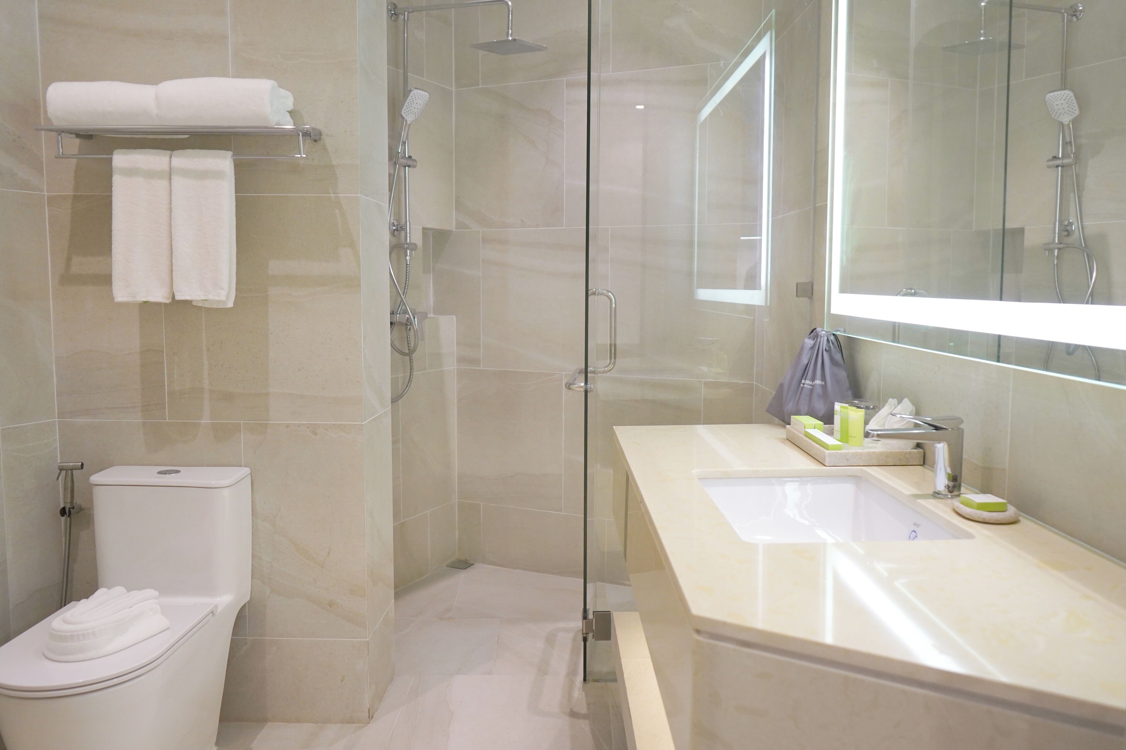 A modern bathroom with a glass-enclosed shower, a toilet, and a vanity with a sink and mirror.