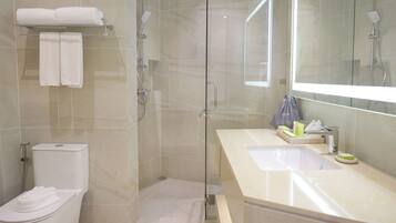 A modern bathroom with a glass-enclosed shower, a toilet, and a vanity with a sink and mirror.
