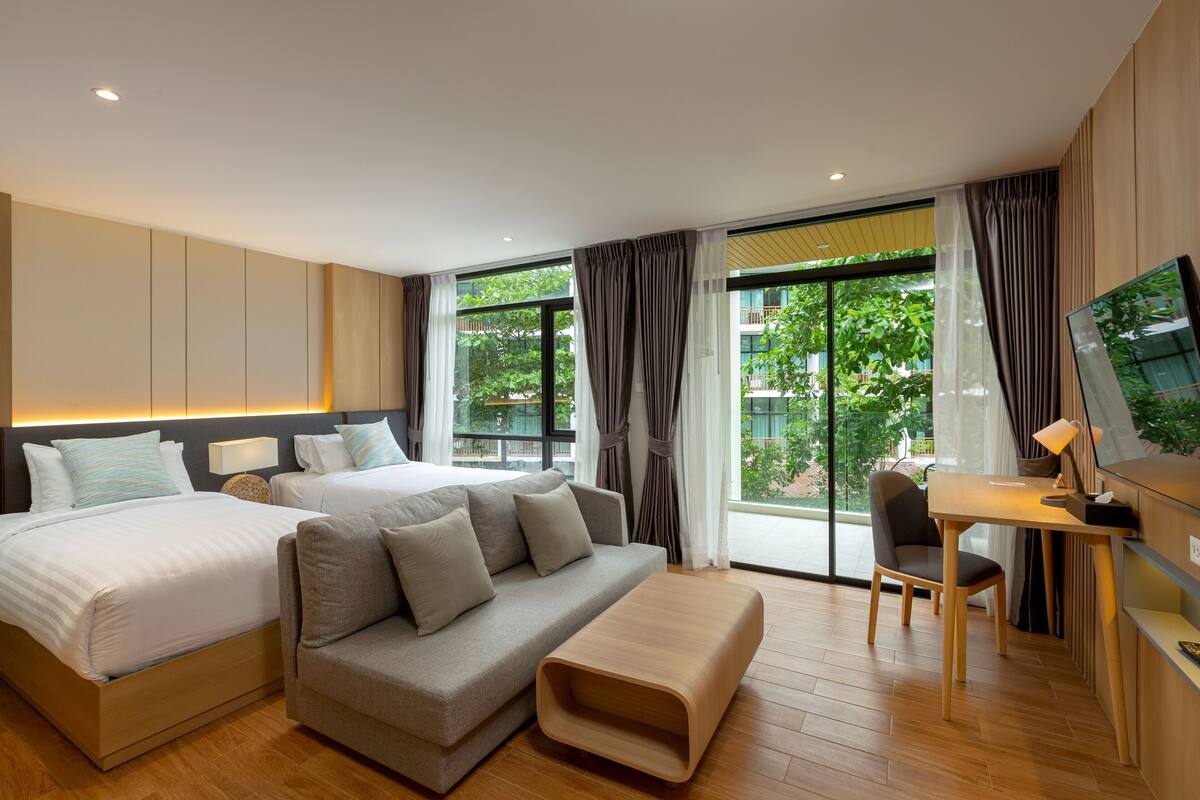 Una habitación de hotel moderna con una cama grande, un sofá, un escritorio y un televisor.
