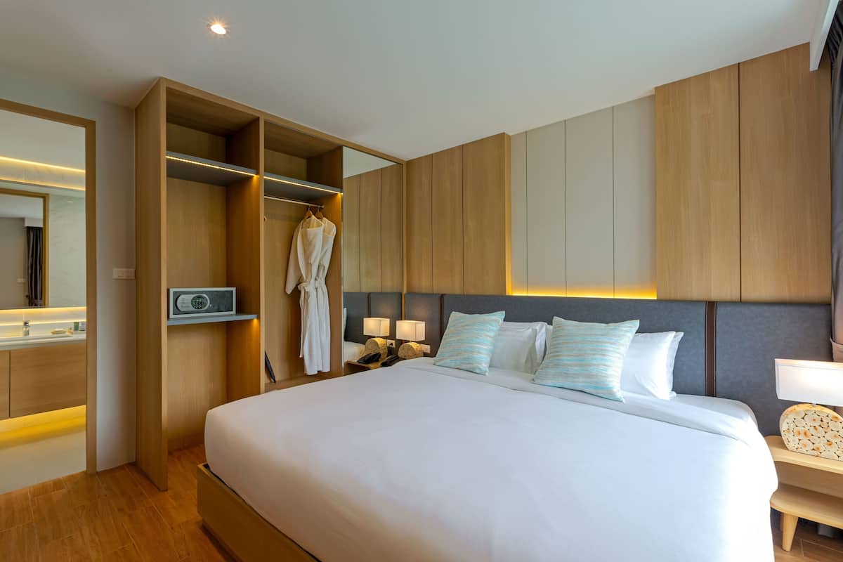 Una habitación de hotel moderna con una cama grande, armario empotrado, lámparas de noche y un espejo.
