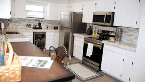 Una cocina moderna con armarios blancos, electrodomésticos de acero inoxidable y una isla central con asientos.