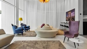 A modern living room with a large window, a chandelier, and a sofa set. - Elegance Suítes Carvalho (São Paulo)