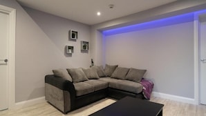A modern living room with a sectional sofa, a black coffee table, and a small side table. - Indigo Apartment - Beautiful 1-bed in Ballycastle (Ballycastle)