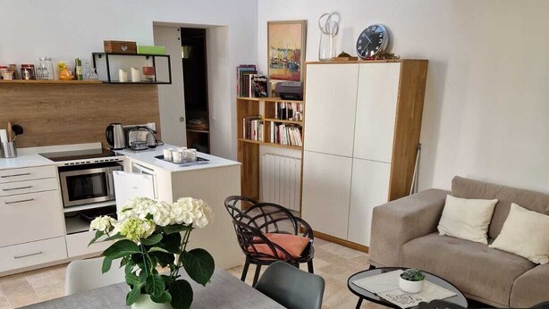 En moderne opholdsstue med spiseplads, sofa, sofabord og et køkken med hårde hvidevarer.