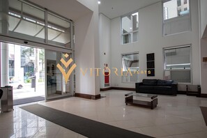 A spacious lobby with a glass door entrance, a black leather sofa, and a coffee table.
