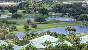 Un campo da golf con uno stagno, palme e un club house.