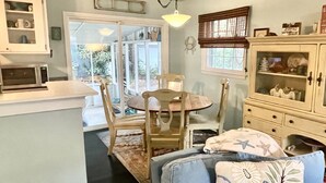 Una cocina acogedora con una mesa de comedor y sillas, un microondas y un armario con puertas de vidrio.