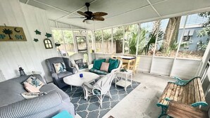 Un espacio al aire libre techado con ventilador de techo, sofá, mesa de centro y mesa de comedor.