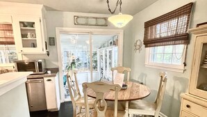Una cocina con mesa, sillas, microondas y refrigerador.