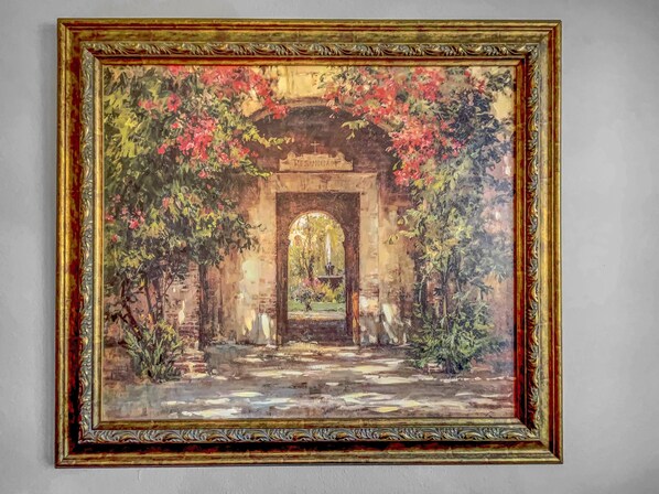 A framed painting of an archway with flowering plants on either side.
