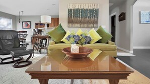 Ein modernes Wohnzimmer mit einer Couch, einem Couchtisch und einem Essbereich im Hintergrund.