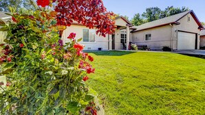 Ein Wohnhaus mit gepflegtem Rasen, ein Haus mit Garage und ein Garten mit roten Blumen.
