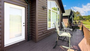 A wooden cabin with a deck, a covered patio, and a view of a golf course. - Cozy Cottage Inside the Premier Old Kinderhook Golf Resort (Camdenton)
