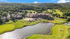 A golf course with a large pond, a clubhouse, and surrounding residential buildings. - Cozy Cottage Inside the Premier Old Kinderhook Golf Resort (Camdenton)
