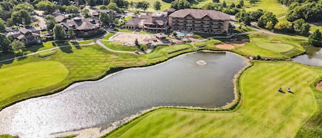 Een golfbaan met een groot vijver, een clubhuis en omliggende woongebouwen.