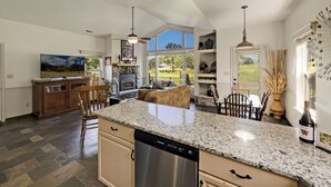 A spacious kitchen with granite countertops, a dishwasher, and a stone fireplace. - Cozy Cottage Inside the Premier Old Kinderhook Golf Resort (Camdenton)