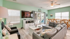 A living room with a sofa, coffee table, and a dining area with chairs and a table.